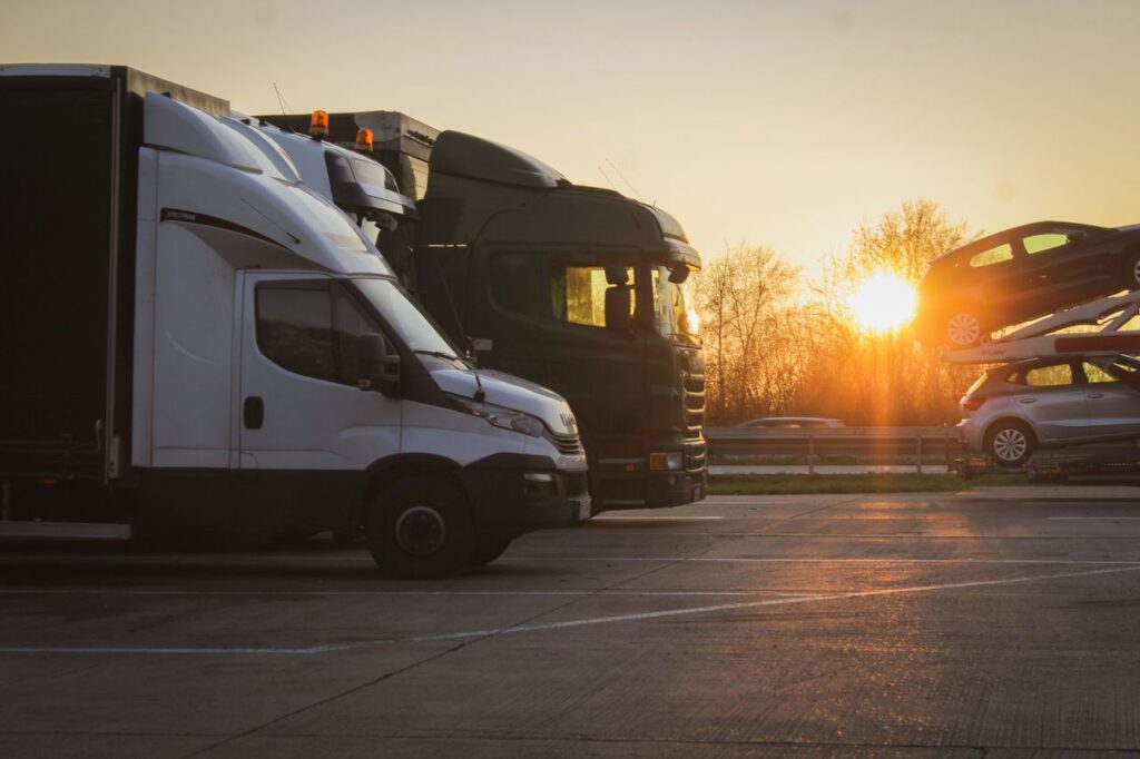 A row of trucks and car transporter parked at sunset in an open parking lot, highlighting the golden hour.
