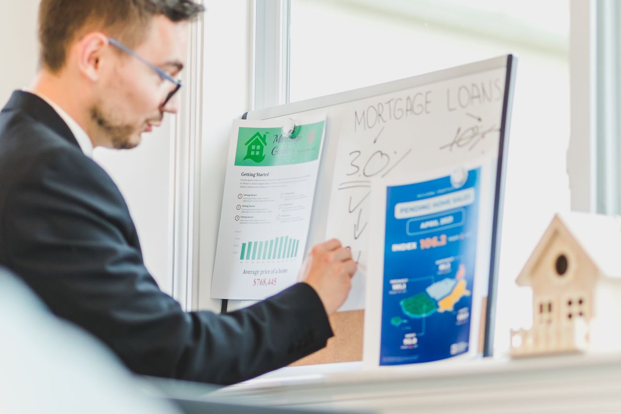 Real estate agent analyzing mortgage loan details on a whiteboard in an office setting.